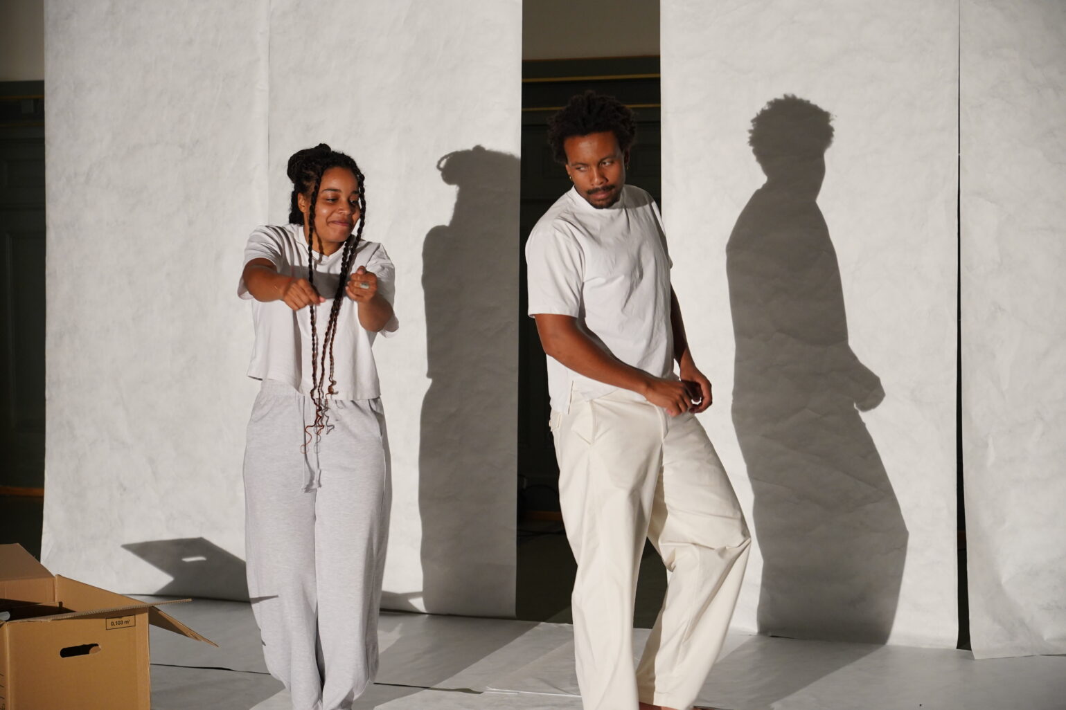 ELLE et LUI sont en mouvement sur scène. ELLE a un sourire timide.